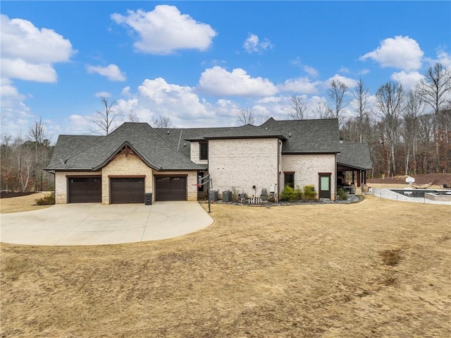 view of front facade featuring brick siding, a shingled roof, concrete driveway, a front yard, and a garage