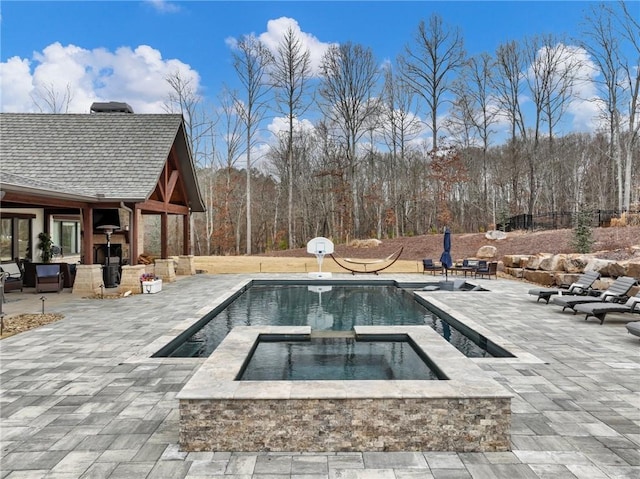 pool featuring an in ground hot tub, an outdoor fireplace, and a patio area