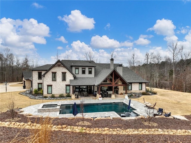 rear view of house featuring a patio, a chimney, outdoor lounge area, an outdoor pool, and an in ground hot tub