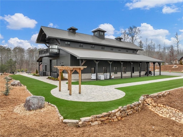 back of house with a patio, a yard, board and batten siding, metal roof, and a balcony