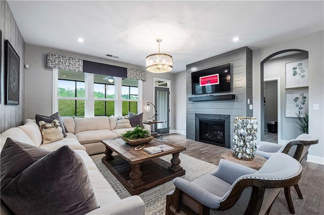 living room with a tiled fireplace, an inviting chandelier, and hardwood / wood-style flooring