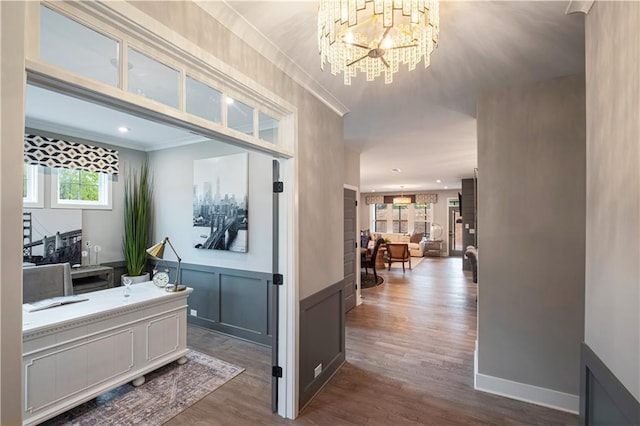 corridor featuring hardwood / wood-style floors, ornamental molding, and an inviting chandelier