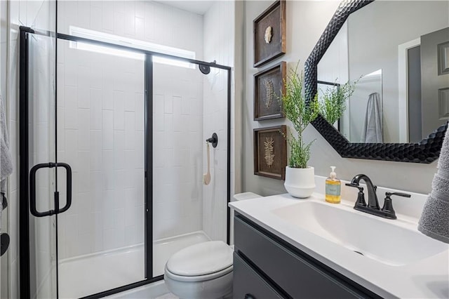 bathroom with toilet, a shower with shower door, and vanity