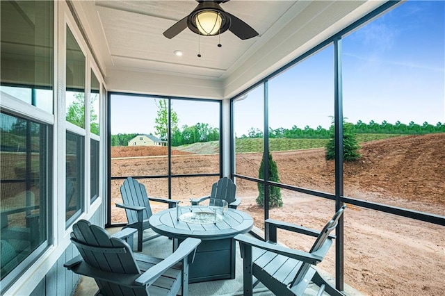 sunroom / solarium with ceiling fan, a wealth of natural light, and a rural view