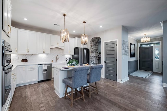 kitchen with stainless steel appliances, dark hardwood / wood-style flooring, a kitchen island, pendant lighting, and white cabinets