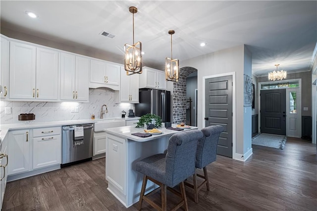 kitchen featuring appliances with stainless steel finishes, a kitchen island, white cabinetry, sink, and hanging light fixtures