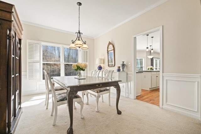 dining area with light carpet, a decorative wall, crown molding, and a wainscoted wall