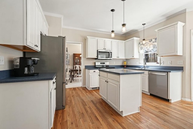 kitchen with dark countertops, crown molding, light wood-style floors, white cabinets, and stainless steel appliances