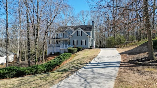 view of front of house featuring aphalt driveway, a porch, and a chimney