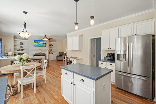 kitchen featuring dark countertops, open floor plan, a fireplace, and stainless steel fridge