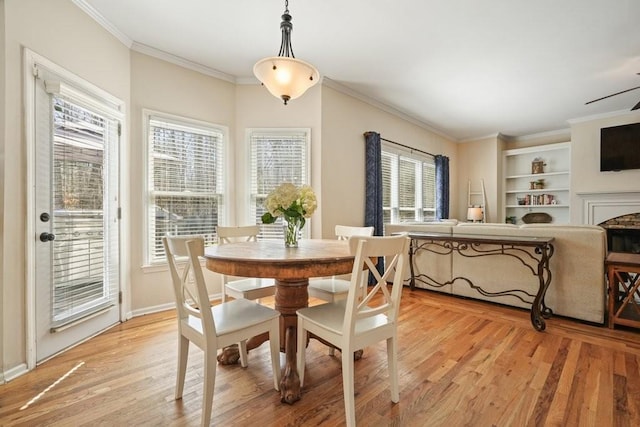 dining room with baseboards, light wood-style floors, ornamental molding, and a fireplace