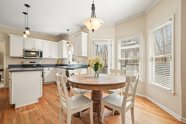 dining room with crown molding, light wood-style flooring, and baseboards