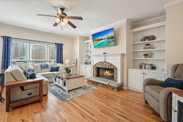 living room featuring light wood finished floors, a fireplace, built in shelves, and ornamental molding