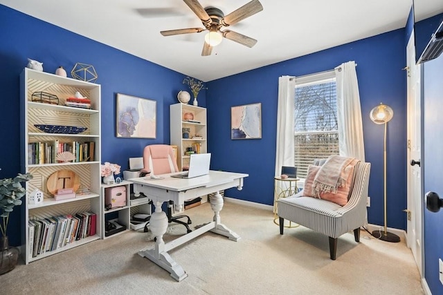 carpeted office space featuring baseboards and a ceiling fan