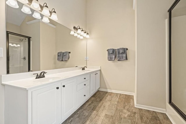 full bathroom with a sink, baseboards, a shower with shower door, and wood finished floors