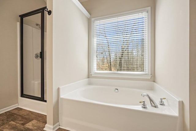 bathroom featuring a stall shower, baseboards, and a garden tub