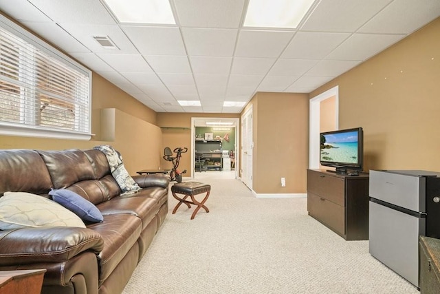 living room featuring baseboards, a paneled ceiling, visible vents, and light carpet