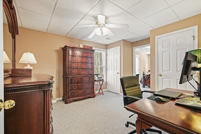 carpeted office space featuring baseboards, a paneled ceiling, and ceiling fan