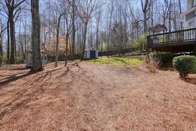 view of yard featuring a wooden deck, a storage shed, and an outdoor structure