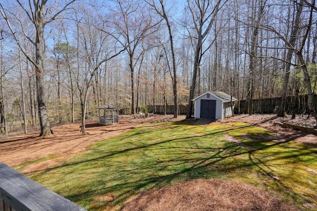 view of yard with an outdoor structure, fence, a wooded view, and a shed