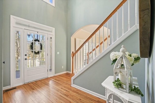 foyer with baseboards, visible vents, a high ceiling, stairs, and wood-type flooring