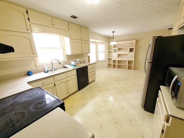542 Banks Rd E, Fayetteville, GA 30214 - kitchen featuring black appliances, light floors, a textured ceiling, hanging light fixtures, and light countertops