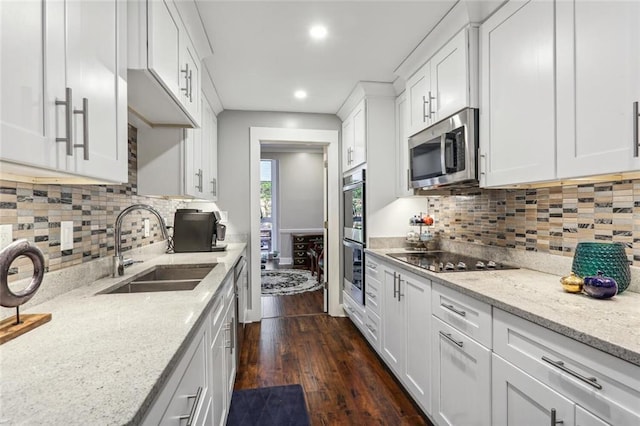 kitchen with white cabinets, black electric cooktop, light stone counters, and sink