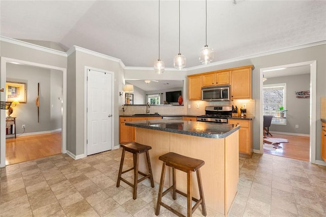 kitchen with a kitchen island, decorative backsplash, appliances with stainless steel finishes, a kitchen breakfast bar, and a sink