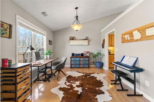 office with visible vents, baseboards, light wood-style floors, and vaulted ceiling