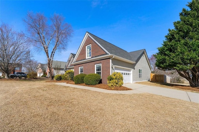 view of side of home with fence, a yard, concrete driveway, an attached garage, and brick siding