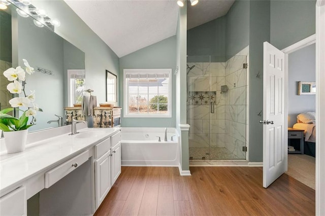 full bath with vanity, wood finished floors, lofted ceiling, a shower stall, and a bath