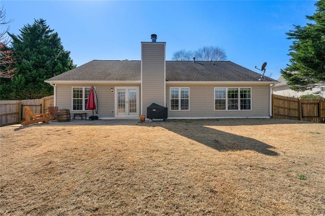 rear view of house with a patio area, french doors, a fenced backyard, and a chimney