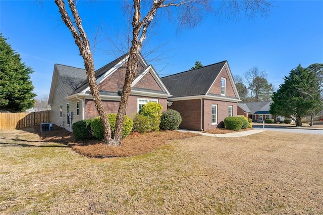 view of home's exterior featuring cooling unit, brick siding, a lawn, and fence