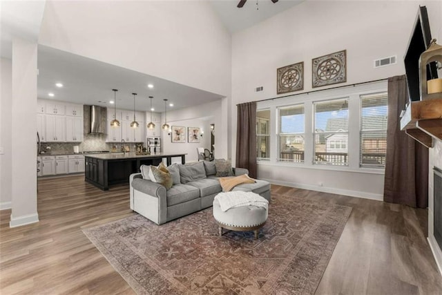 living room with baseboards, visible vents, a ceiling fan, and wood finished floors