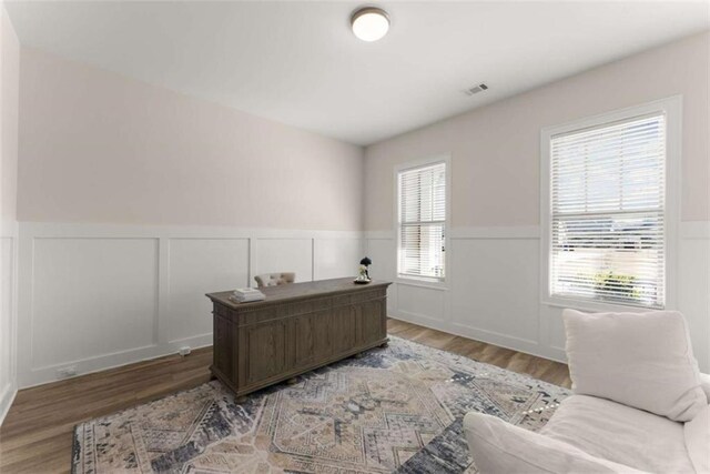 office with a wainscoted wall, visible vents, and wood finished floors