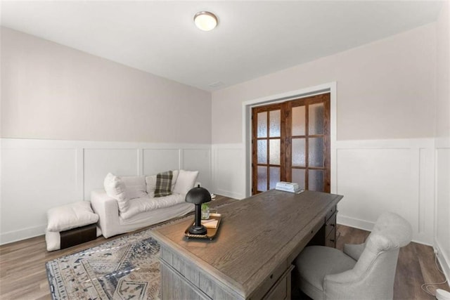 home office featuring a wainscoted wall and wood finished floors