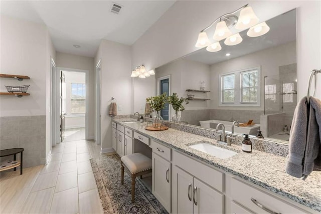 full bathroom with a sink, a bath, tiled shower, and visible vents