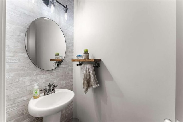 bathroom featuring a sink and brick wall
