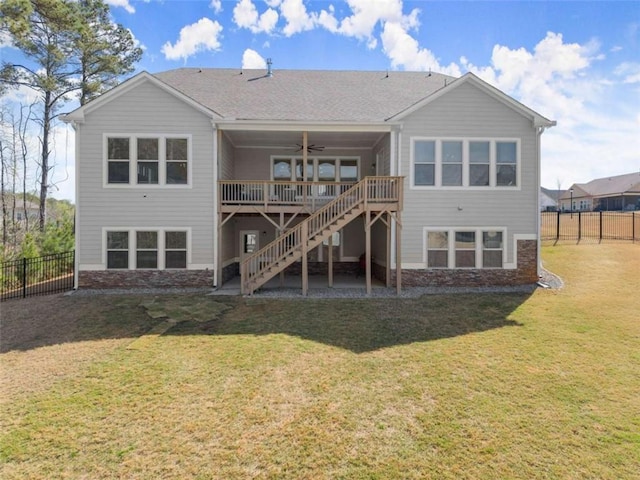 back of property with ceiling fan, stairway, a deck, fence private yard, and a yard