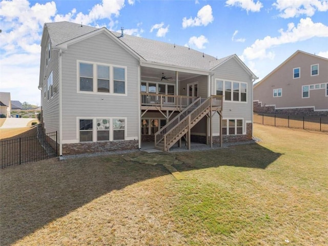 back of property with stone siding, stairs, a fenced backyard, a ceiling fan, and a yard