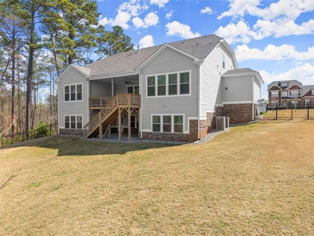 rear view of house featuring stairs, stone siding, fence, a lawn, and ceiling fan