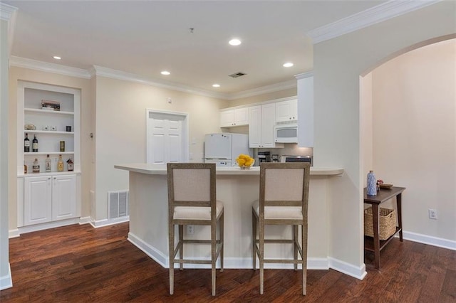 2400 Cumberland Pkwy SE Unit 613, Atlanta, GA 30339 - kitchen featuring white microwave, refrigerator, arched walkways, dark wood-style flooring, and a peninsula