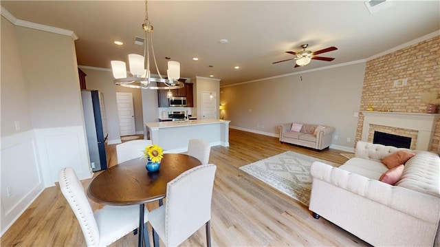dining area featuring crown molding, ceiling fan with notable chandelier, and light wood-type flooring