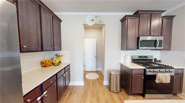 kitchen featuring light wood-style floors, light countertops, crown molding, and stainless steel appliances