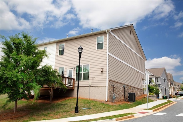 view of property exterior featuring central air condition unit, a deck, and a residential view