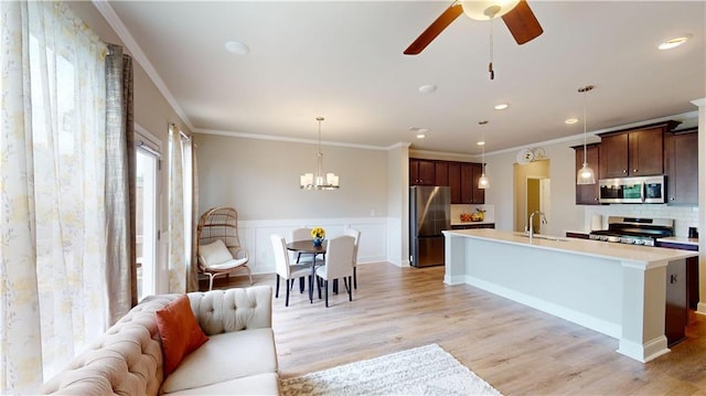 kitchen featuring a sink, light countertops, ceiling fan with notable chandelier, open floor plan, and stainless steel appliances