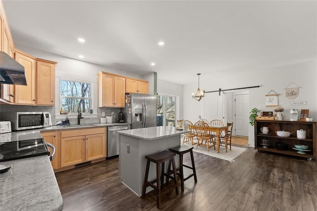 kitchen with decorative backsplash, appliances with stainless steel finishes, a center island, light brown cabinetry, and a sink