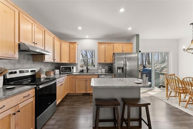 kitchen with decorative backsplash, light stone countertops, stainless steel appliances, light brown cabinetry, and under cabinet range hood