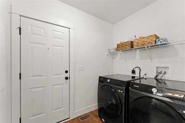 clothes washing area with laundry area, visible vents, wood finished floors, and washing machine and clothes dryer