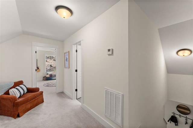 corridor featuring light carpet, lofted ceiling, visible vents, and baseboards